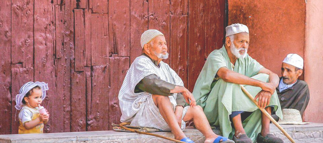 Moroccan elderly people and a toddler sitting on the door step