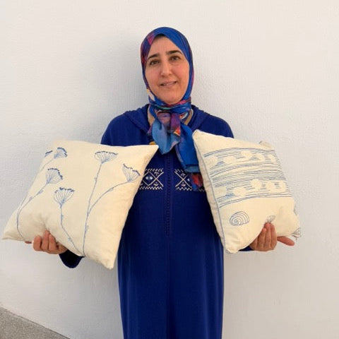 Woman holding two decorative pillows against a white wall artisan morocco

