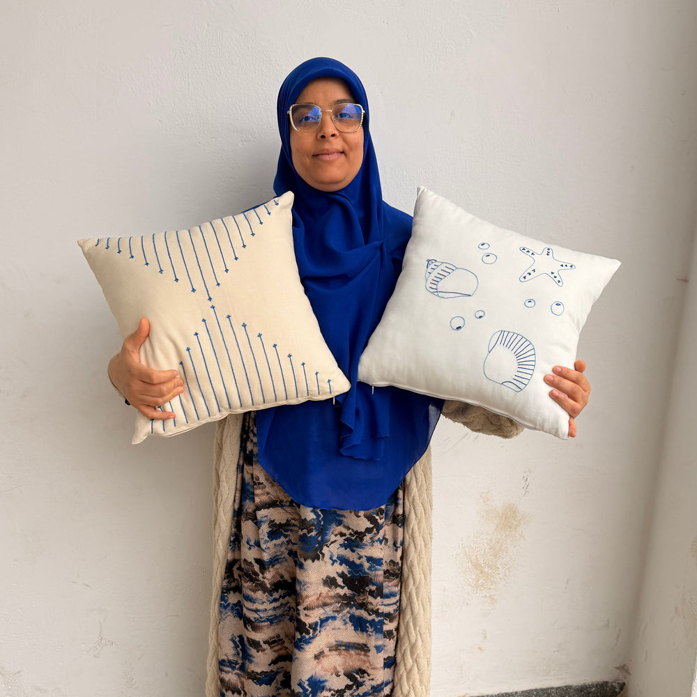 Person holding two decorative pillows on a white surface artisans morocco